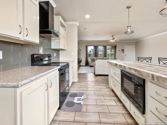 a large kitchen with stainless steel appliances granite countertop a stove a sink and a microwave