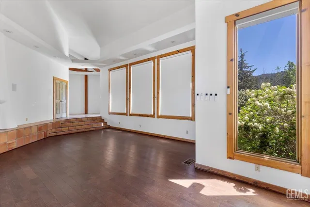 an empty room with wooden floor staircase and windows