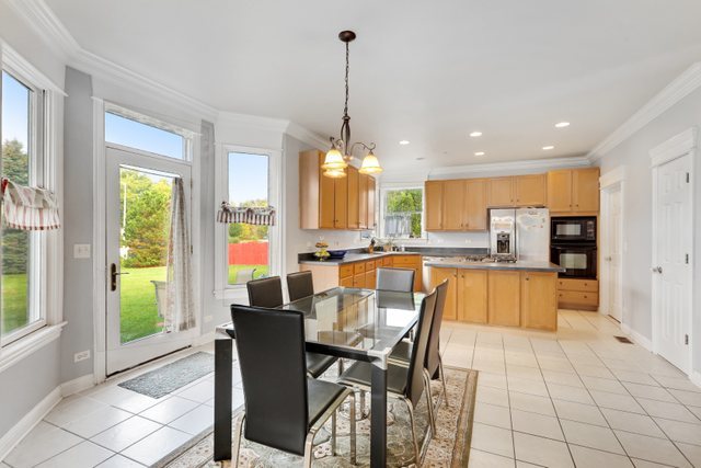 1350 Hunters Ridge West Hoffman Estates, IL 60192 - Photo 12 of 41 a dining hall with stainless steel appliances kitchen island granite countertop a refrigerator a sink a dining table and chairs with wooden floor