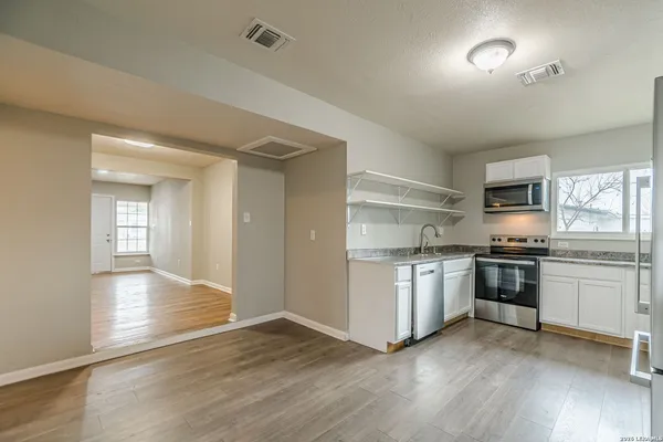 a kitchen with stainless steel appliances granite countertop a sink and cabinets with wooden floor