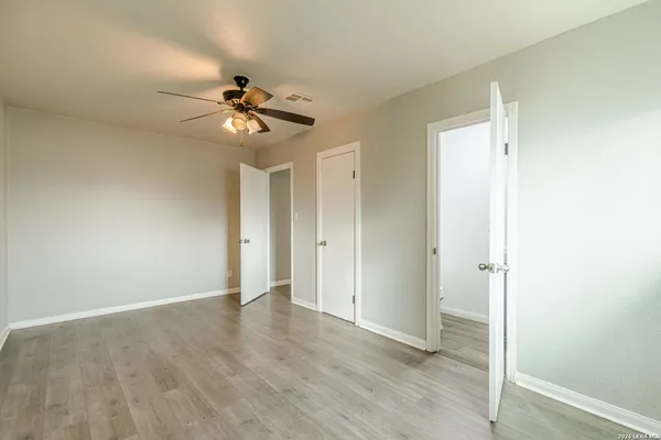 a view of empty room with wooden floor and fan