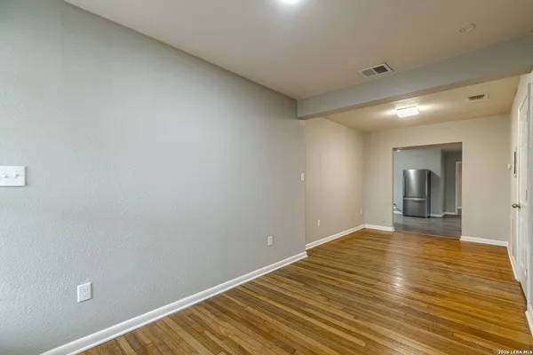 a view of an empty room with wooden floor and window