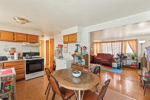a living room with stainless steel appliances furniture a rug and a kitchen view