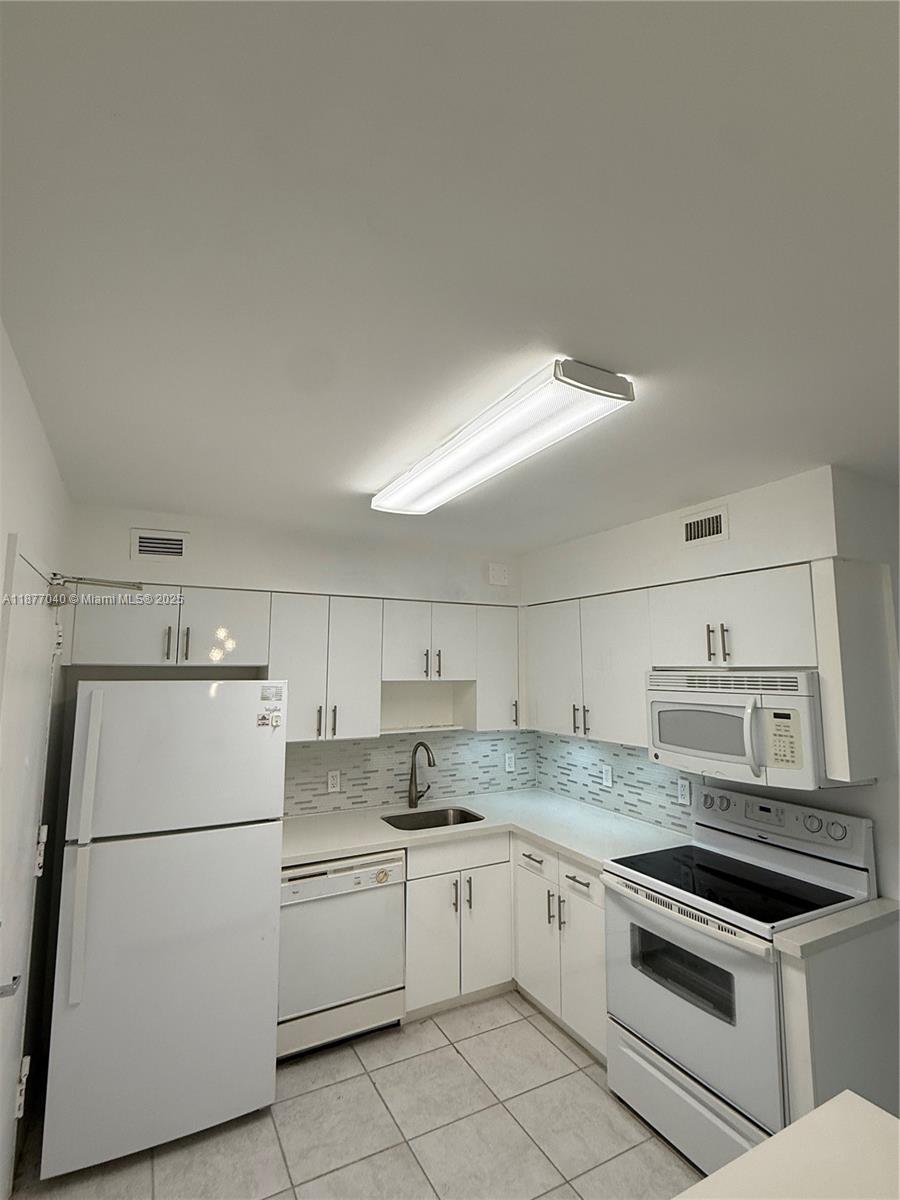5161 Collins Avenue, Unit 511 Miami Beach, FL 33140 - Photo 2 of 29 a kitchen with a white cabinets and white appliances