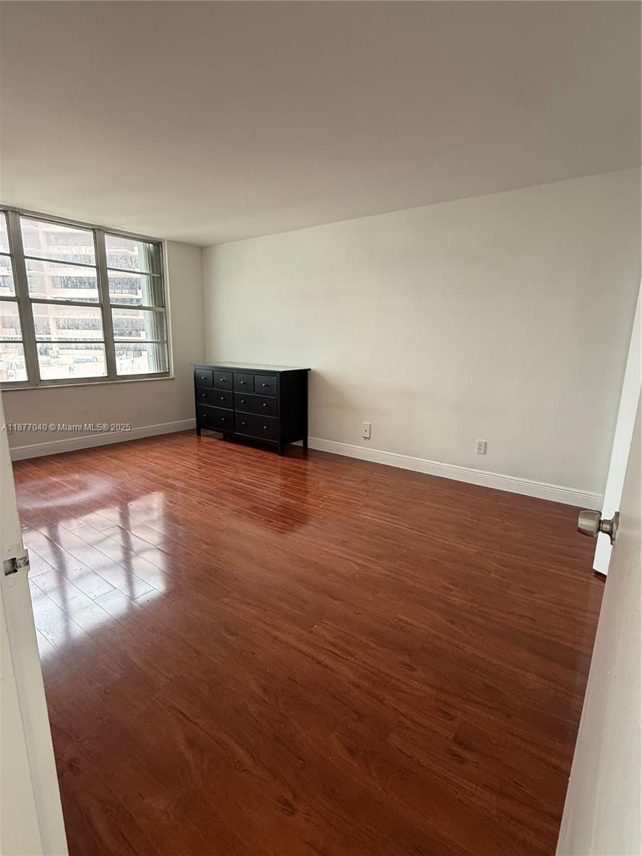 5161 Collins Avenue, Unit 511 Miami Beach, FL 33140 - Photo 4 of 29 an empty room with wooden floor and windows