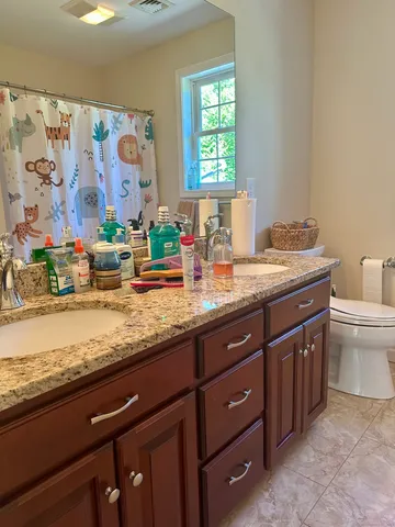 a bathroom with a granite countertop sink a toilet and a window