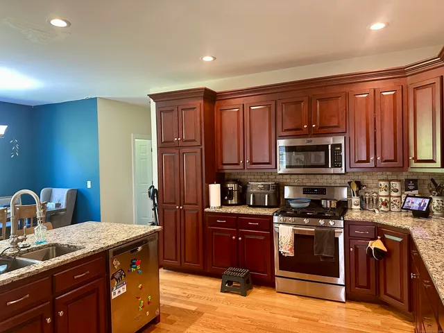 a kitchen with stainless steel appliances granite countertop a stove a sink dishwasher and a refrigerator