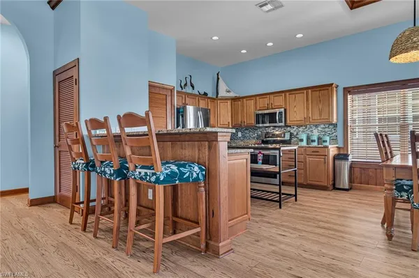 a kitchen with stainless steel appliances kitchen island granite countertop a stove a refrigerator and a dining table with wooden floor