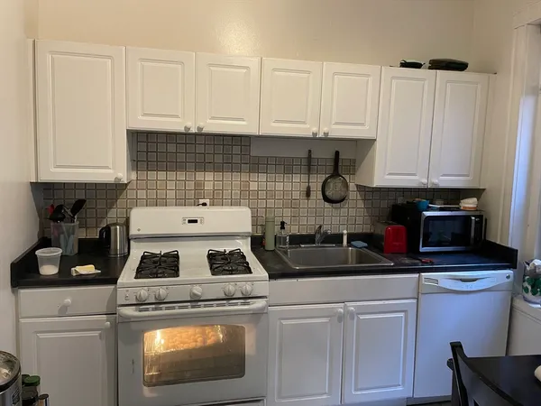 a kitchen with a stove and white cabinets