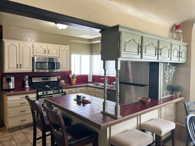 40 South State Street Scipio, UT 84656 - Photo 13 of 39 Kitchen with tile counters, a breakfast bar area, appliances with stainless steel finishes, and a peninsula