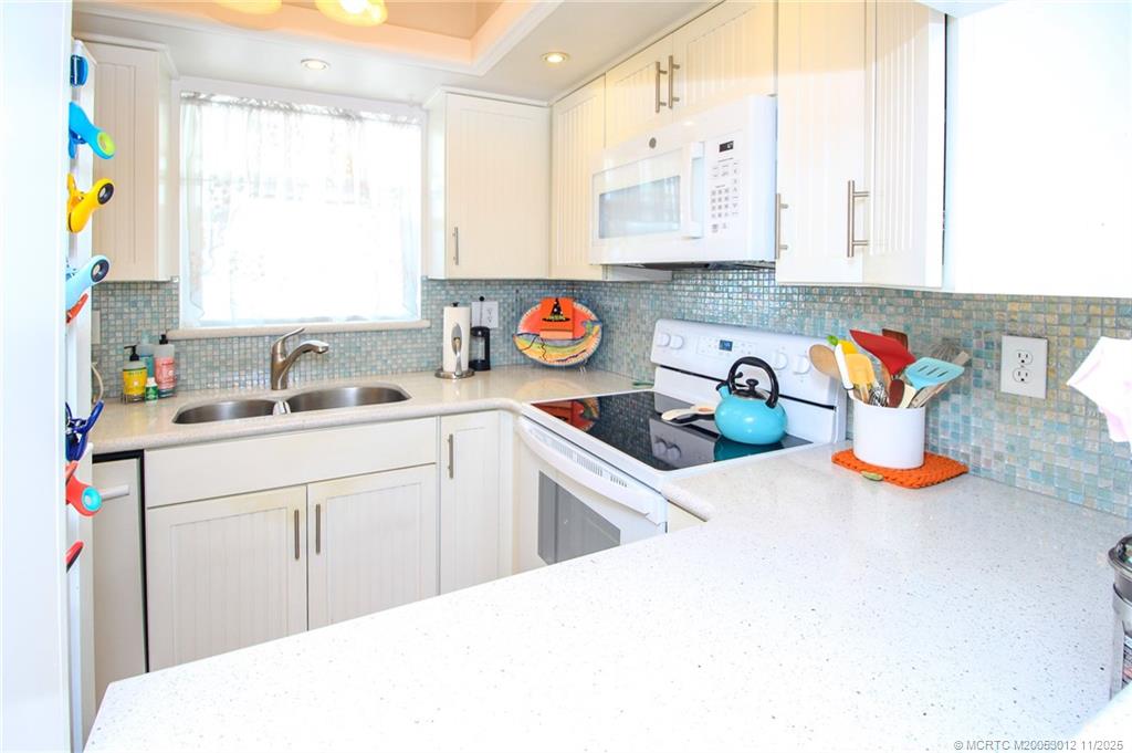 2929 Southeast Ocean Boulevard, Unit 1189 Stuart, FL 34996 - Photo 6 of 34 a kitchen with stainless steel appliances a sink a stove and white cabinets