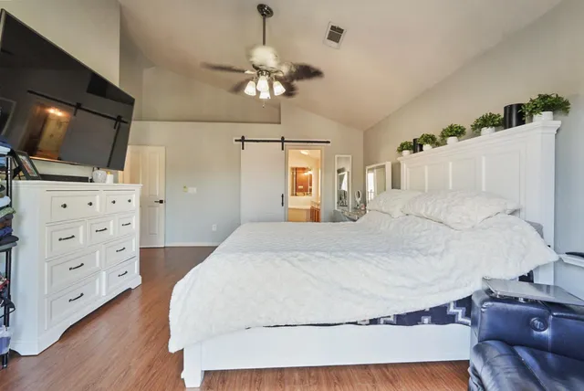 a spacious bedroom with a bed and a flat screen tv