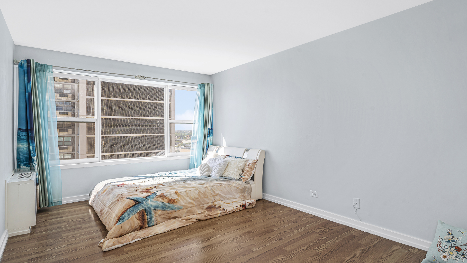 6157 North Sheridan Road, Unit 18K Chicago, IL 60660 - Photo 9 of 14 a bed sitting in a bedroom next to a window and wooden floor