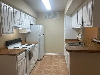 a kitchen with granite countertop a sink a stove and cabinets
