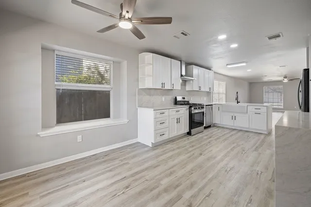 a large kitchen with stainless steel appliances granite countertop a stove a sink dishwasher and a refrigerator with wooden floor