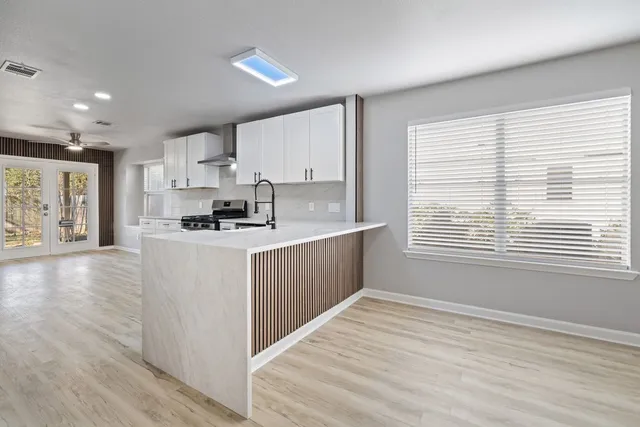 a kitchen with stainless steel appliances granite countertop a stove a sink and white cabinets
