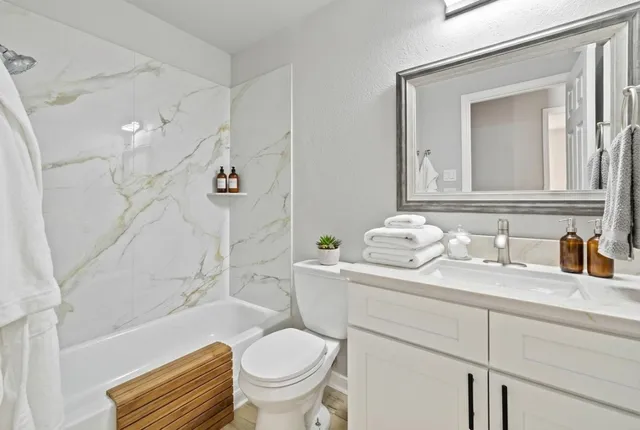 a bathroom with a granite countertop toilet sink and mirror
