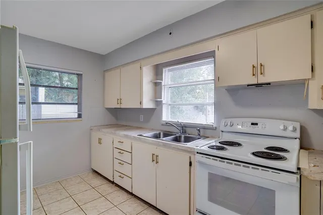 a kitchen with white cabinets appliances a sink and a window