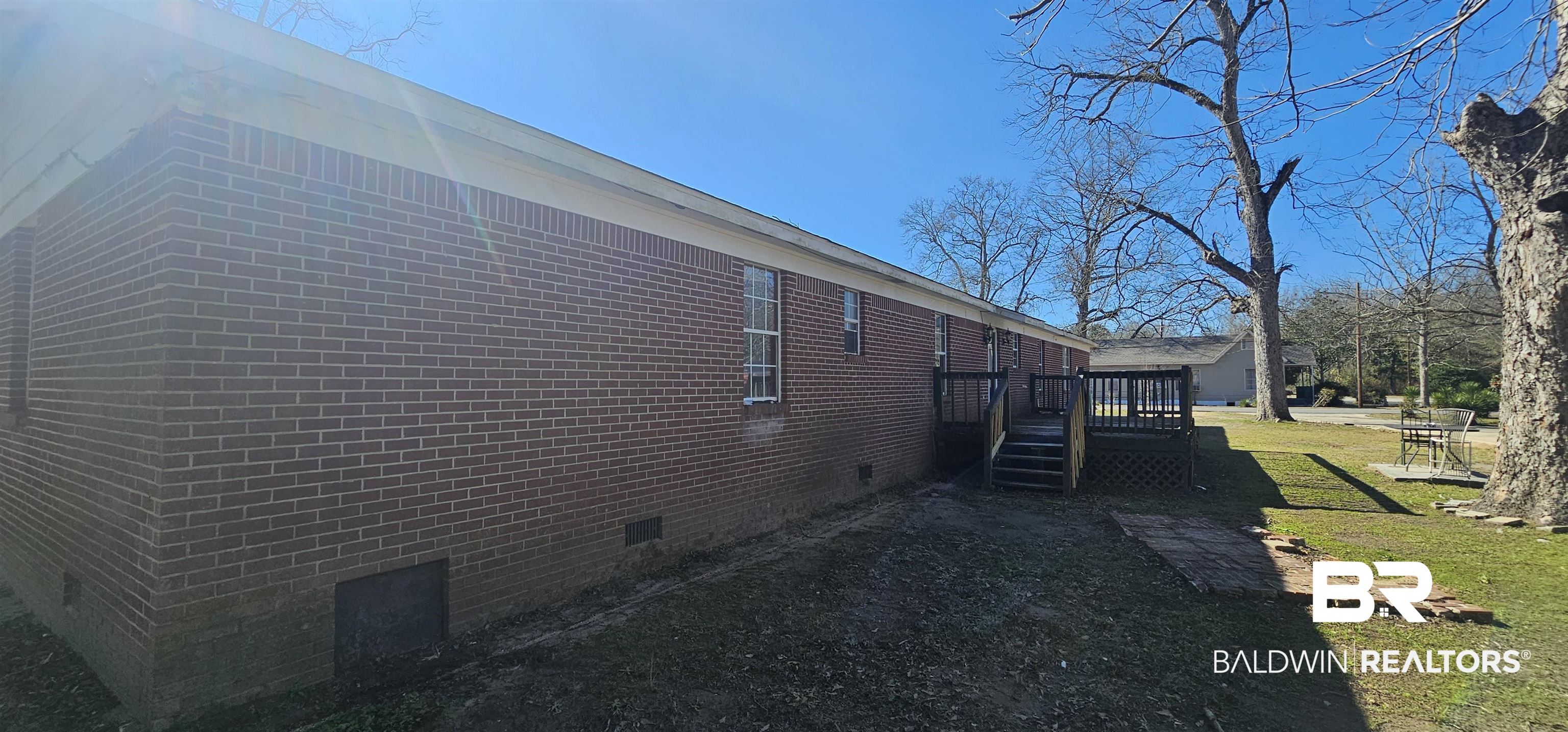 151 Bullard Street Atmore, AL 36502 - Photo 35 of 38 View of side of property featuring crawl space, a wooden deck, a lawn, and brick siding