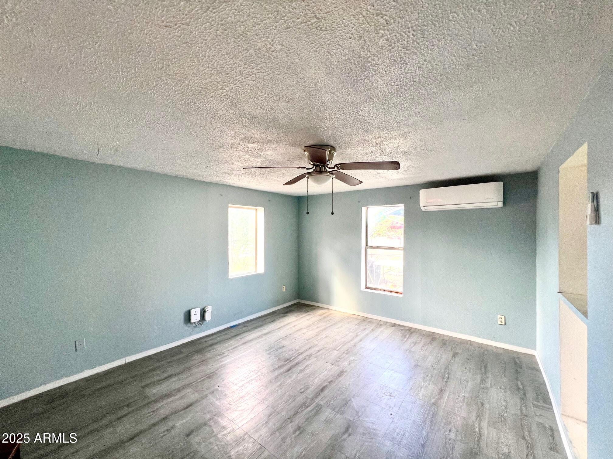2002 West Lawrence Road Phoenix, AZ 85015 - Photo 16 of 22 an empty room with wooden floor chandelier fan and windows