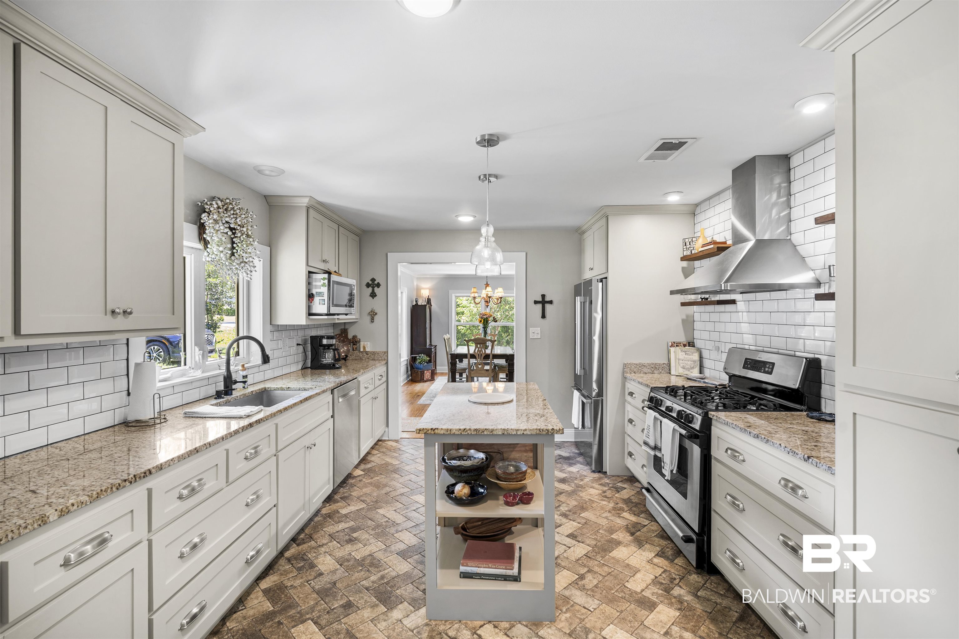 1615 5th Street Daphne, AL 36526 - Photo 6 of 28 Bright kitchen featuring a central island, white shaker cabinetry, stainless steel appliances, subway tile backsplash, and light-toned granite countertops