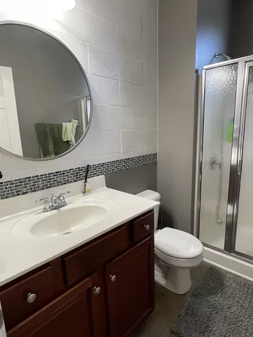 a bathroom with a sink a toilet a mirror and shower