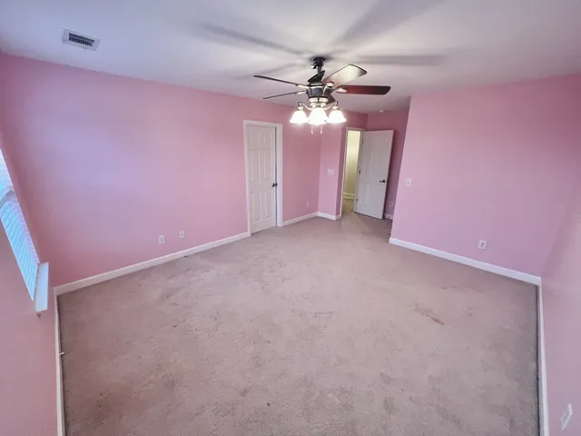 a view of an empty room with a chandelier fan