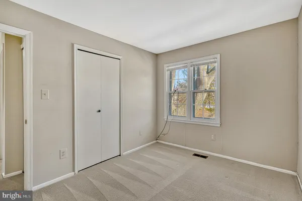 a view of an empty room with window and closet area