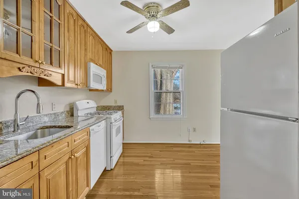 a kitchen with stainless steel appliances granite countertop a sink and cabinets with wooden floor