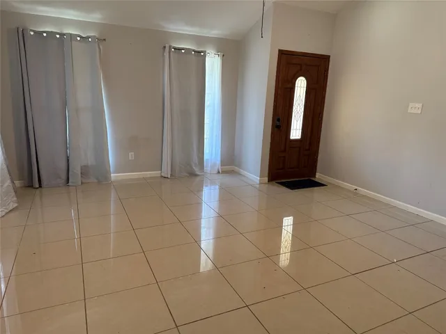 a view of an empty room with window and chandelier fan