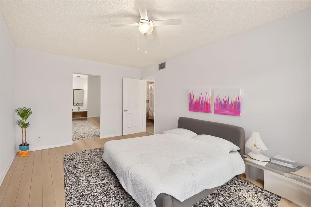 130 Cypress Club Drive, Unit 307 Pompano Beach, FL 33060 - Photo 14 of 35 a bedroom with a bed and a chandelier