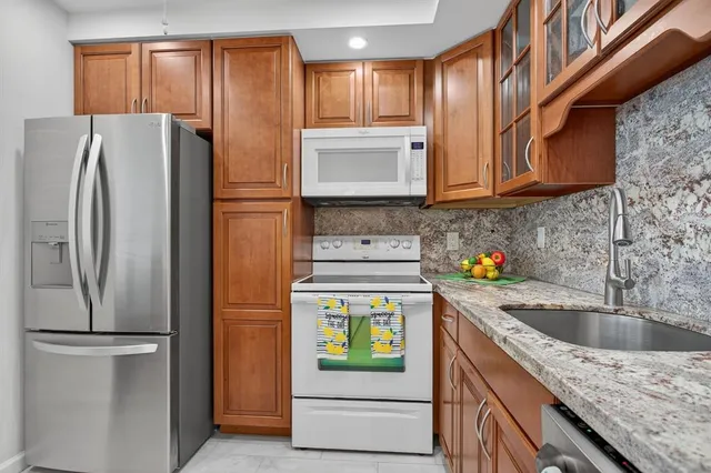 a kitchen with stainless steel appliances granite countertop a refrigerator and a sink