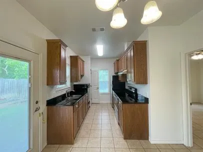 a kitchen with granite countertop a refrigerator a stove top oven a sink and dishwasher