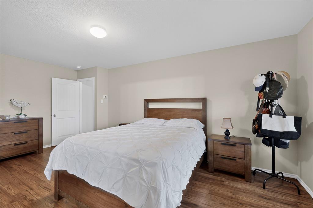 1409 Slate Street Princeton, TX 75407 - Photo 18 of 36 Bedroom featuring wood-finish flooring, neutral wall tones, a solid core door, and a flush-mount ceiling light