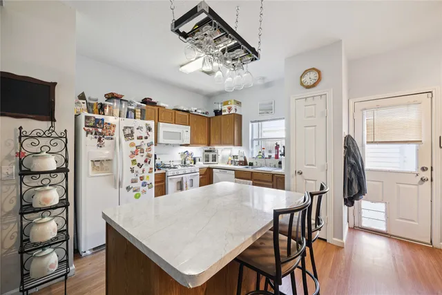 a kitchen with stainless steel appliances kitchen island granite countertop a table chairs and a refrigerator