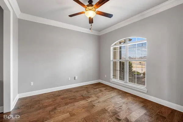 a view of an empty room with window and a ceiling fan