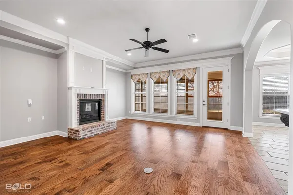 a view of an empty room with wooden floor fireplace and a window