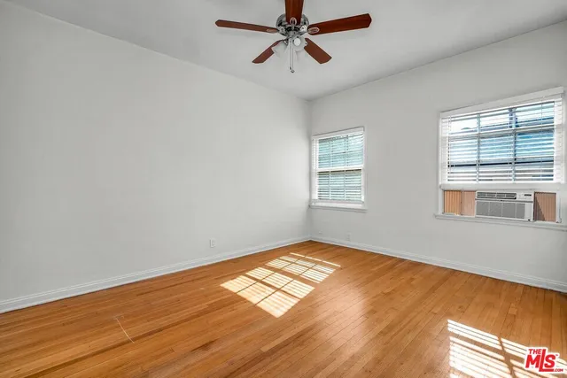 a view of empty room with wooden floor and fan