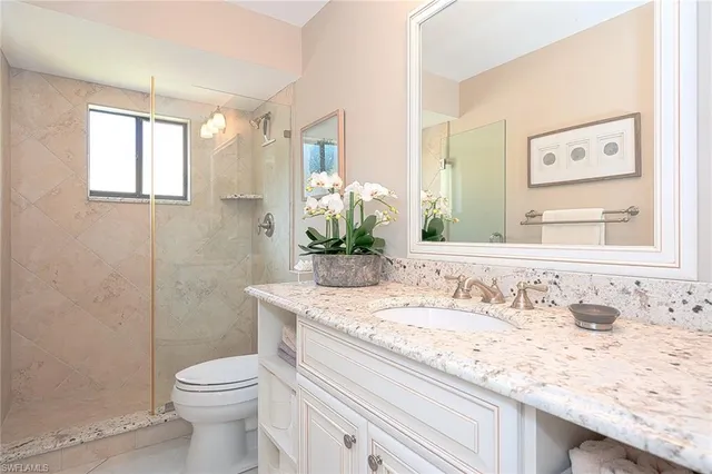 a bathroom with a granite countertop sink a toilet and a mirror