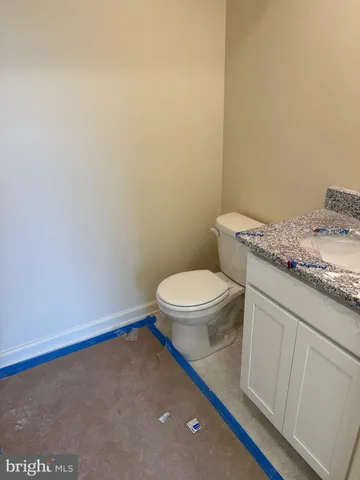 a bathroom with a granite countertop sink and a toilet