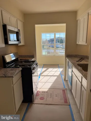 a kitchen with granite countertop a stove a sink and a microwave