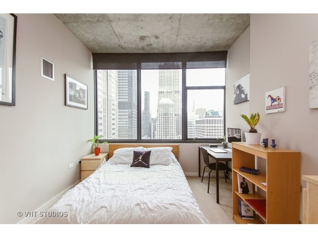 235 West Van Buren Street, Unit 3315 Chicago, IL 60607 - Photo 6 of 23 a bedroom with a bed a table and a large window