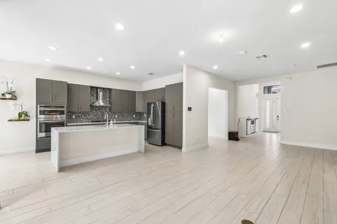 a large kitchen with stainless steel appliances a large counter top a sink and a refrigerator