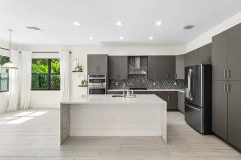 a large white kitchen with a large window and stainless steel appliances
