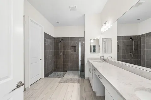 a spacious bathroom with a double vanity sink a large mirror and shower