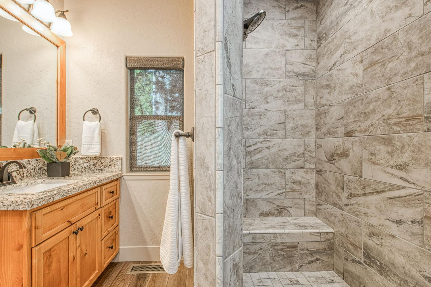 41876 Timber View Lane Shaver Lake, CA 93664 - Photo 51 of 85 a bathroom with a granite countertop sink a mirror and a shower