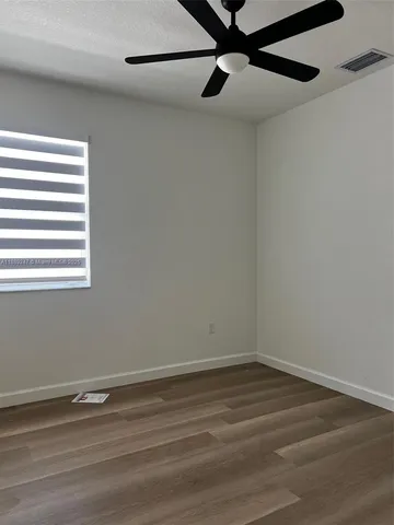 a view of a small space with wooden floor a ceiling fan