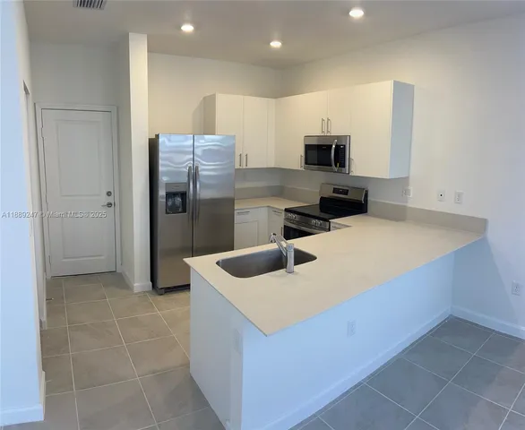 a kitchen with stainless steel appliances a refrigerator sink and microwave