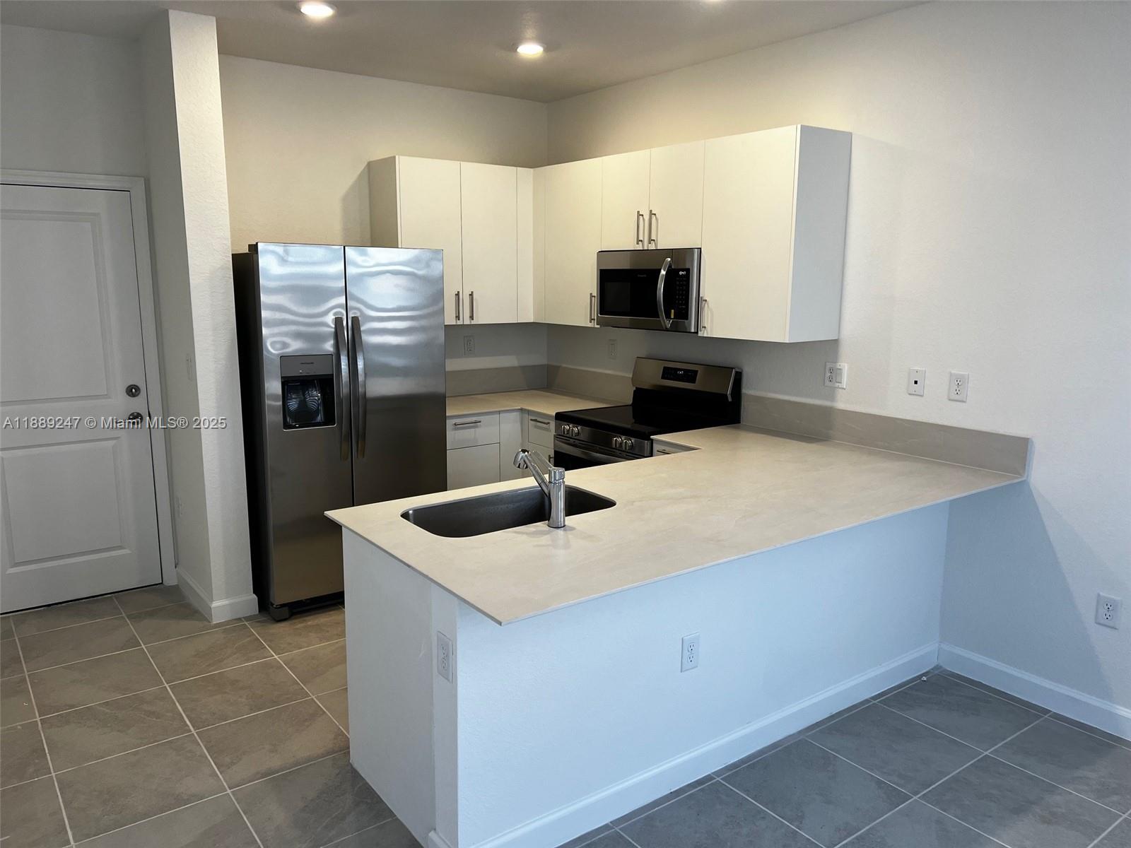 2651 Southeast 24th Drive Homestead, FL 33035 - Photo 8 of 40 a kitchen with stainless steel appliances a sink a stove a refrigerator and cabinets