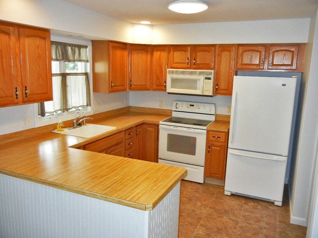 399 Bridge Road, Unit E Northampton, MA 01062 - Photo 2 of 17 a kitchen with stainless steel appliances granite countertop a refrigerator a stove and a sink with wooden floors